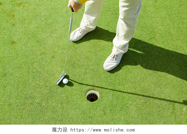 在高尔夫球场一个男人在打着高尔夫球在阳光明媚的日子里, 活跃的男子拿着高尔夫球杆, 同时要把它打到绿地的洞里